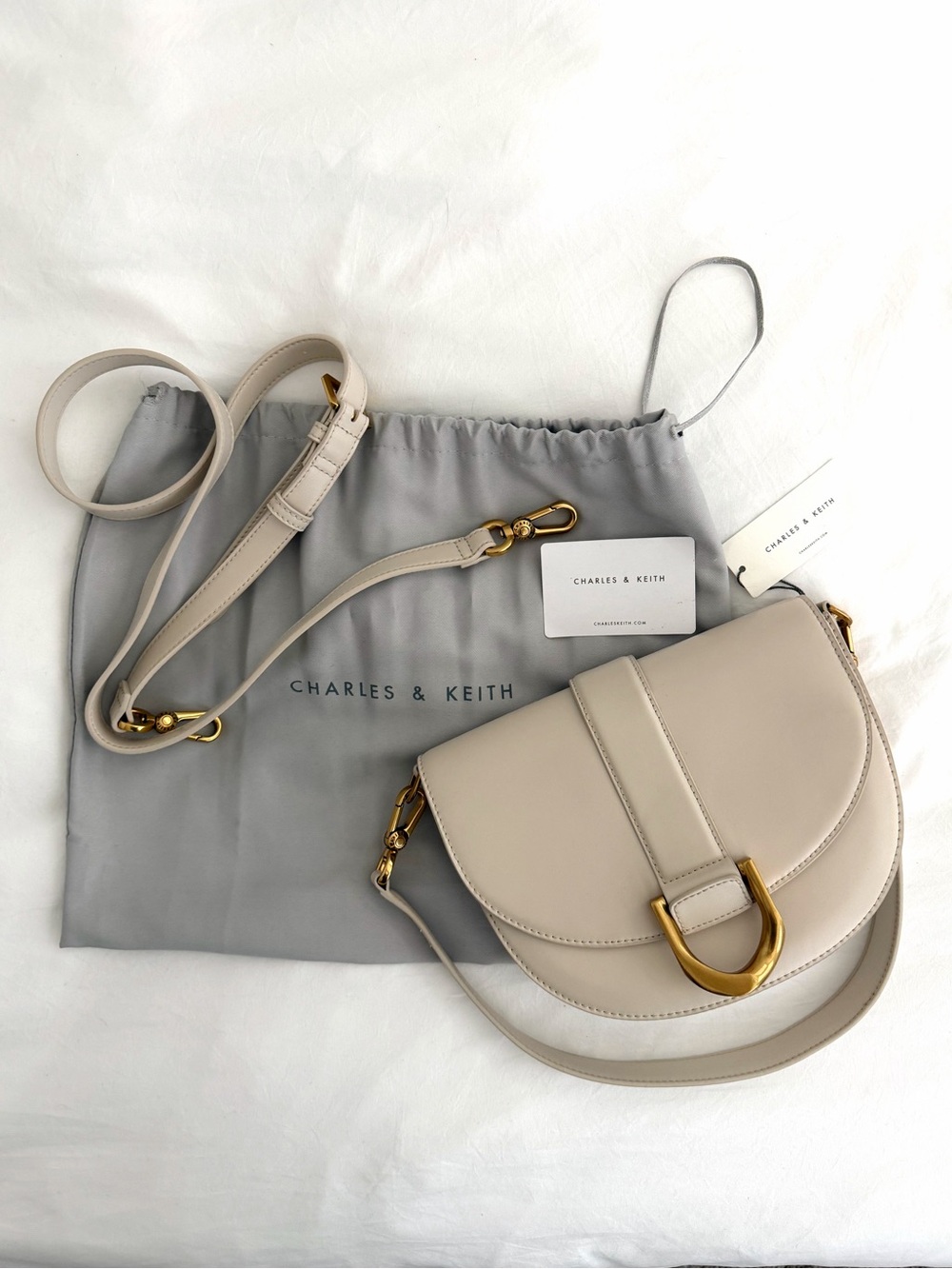Charles & Keith Light Beige Saddle Crossbody Bag with Gold Hardware